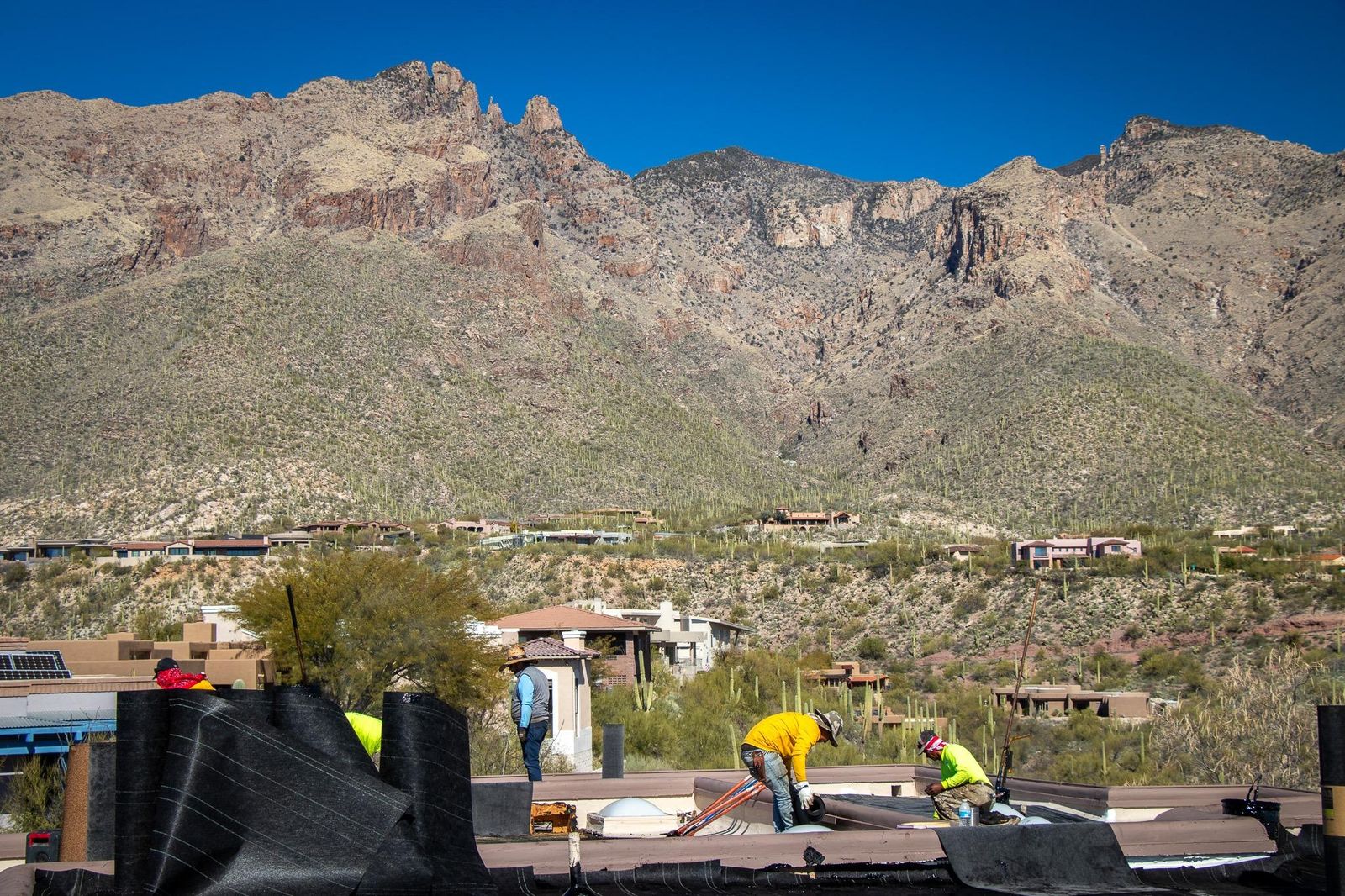Camelback Roofing crew working on a flat roof with Catalina Mountains in the background